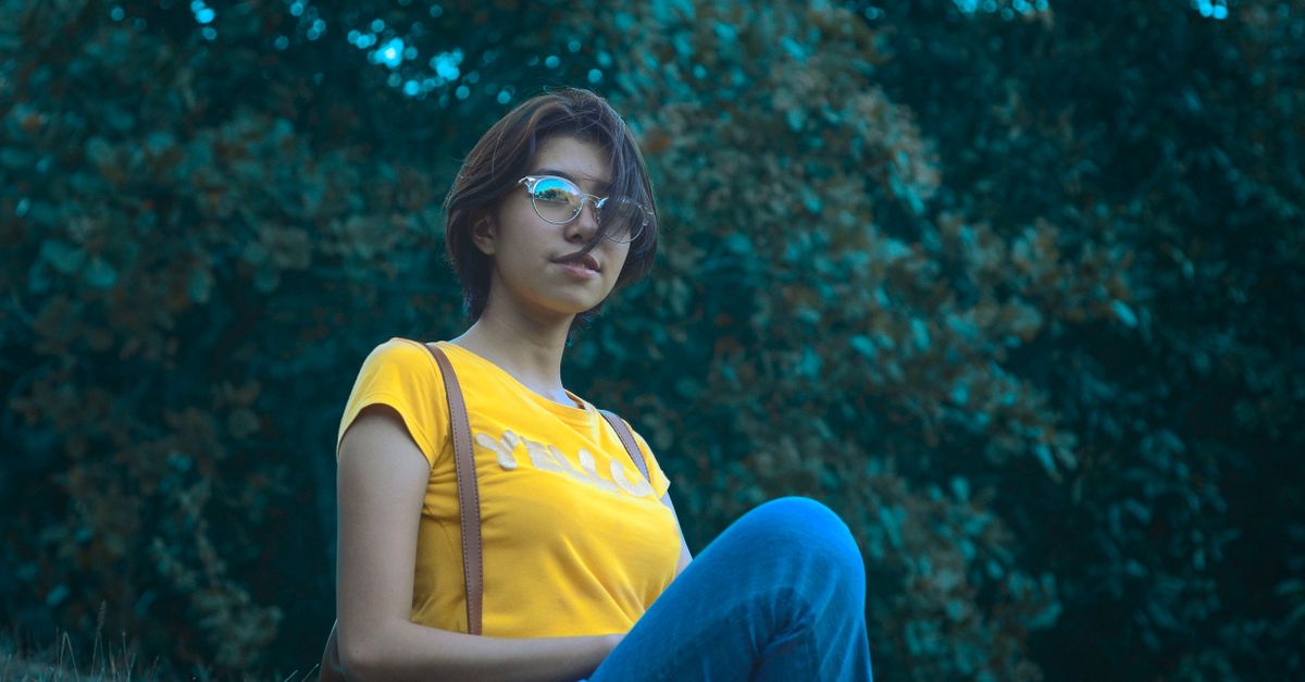 Persona sentada al aire libre con postura tranquila y manos sobre las rodillas